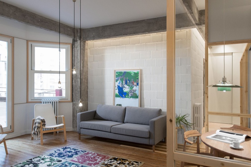 Sofa màu ghi được kê sát tường gạch trần màu trắng, thêm điểm nhấn từ ánh sáng thả trần, dịu dàng Nhà đẹp