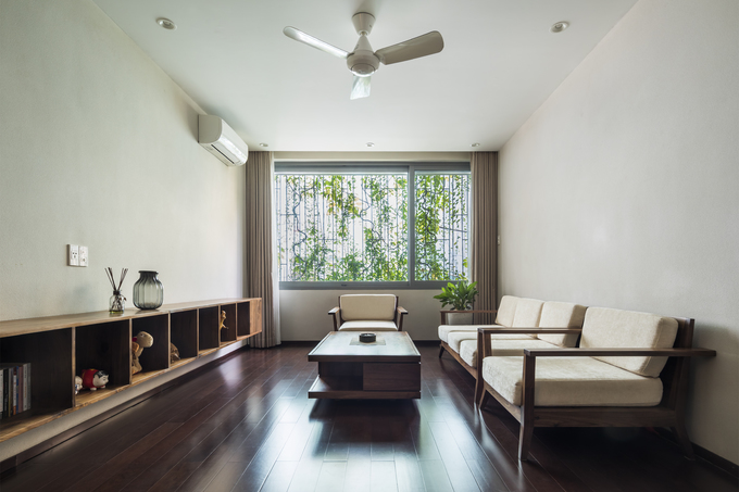 Ảnh chụp một phòng khách bố trí đơn giản, có một khung cửa sổ mở ra bên ngoài có cây xanh phòng khách thoáng đãng