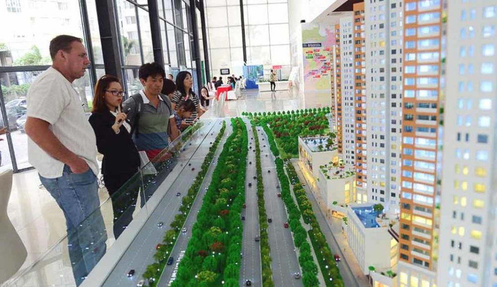 Một nhóm người ngoại quốc đang đứng xem mô hình một dự án chung cư người nước ngoài mua nhà
