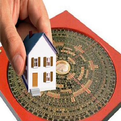 Ảnh chụp một bàn tay đang cầm mô hình ngôi nhà, bên dưới là la kinh phong thủy làm nhà năm 2019