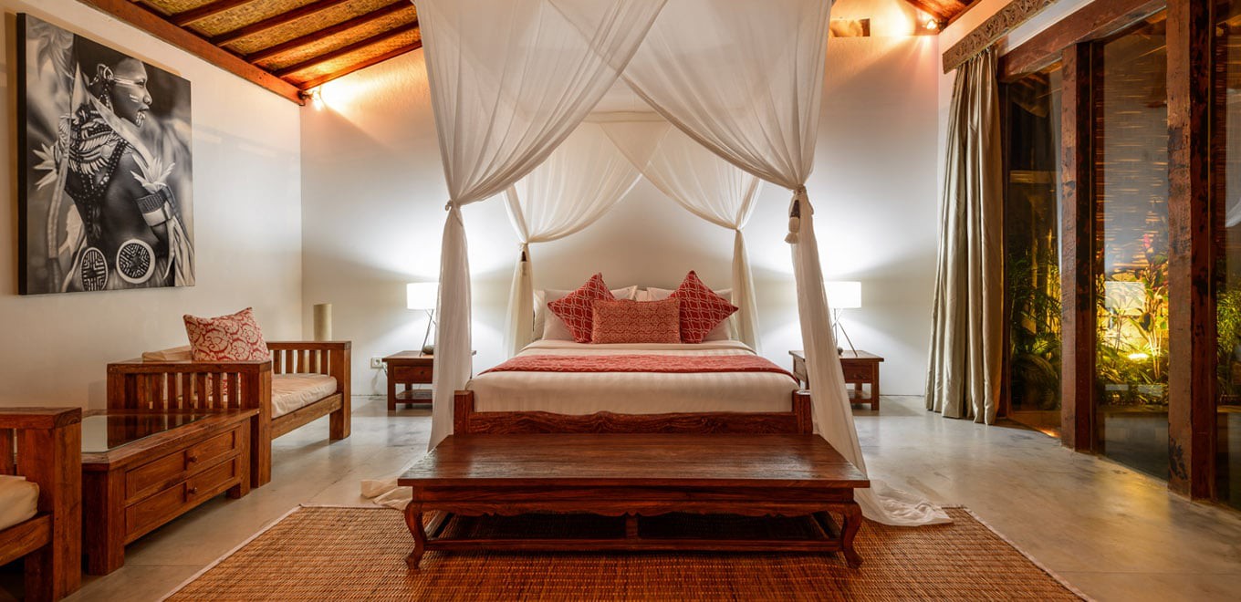 Phòng ngủ trong Biệt thự Ace ở Bali có phòng ngủ chính được trang trí theo phong cách của các resort miền nhiệt đới mang đến sự thoải mái và thư giãn với gam màu đỏ và nội thất gỗ tối màu. phòng ngủ biệt thự nhiệt đới