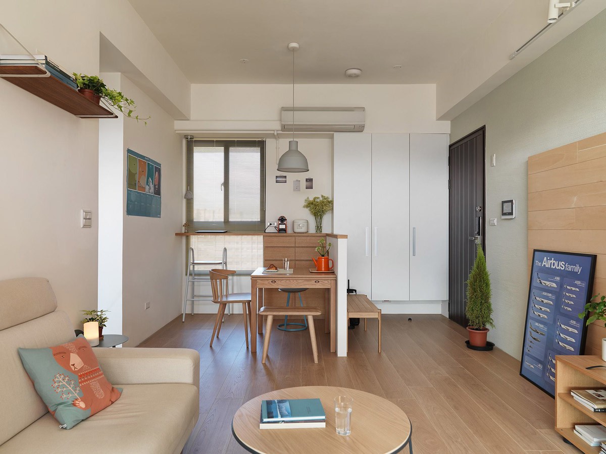 Phòng khách và phòng ăn sử dụng nội thất gỗ, cây xanh. Căn phòng với sofa, bàn ghế kệ gỗ, một vài chậu cây xanh.