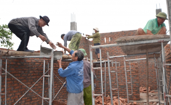 Một nhóm đàn ông đang xây ngôi nhà bằng gạch.