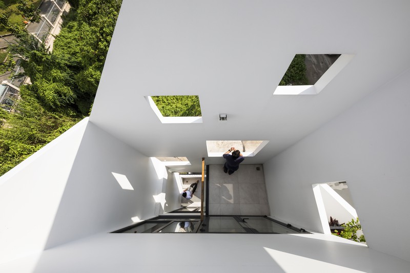 Góc chụp từ trên xuống bên trong một ngôi nhà màu trắng, hai người đang đứng và ngồi dưới chân cầu thang.